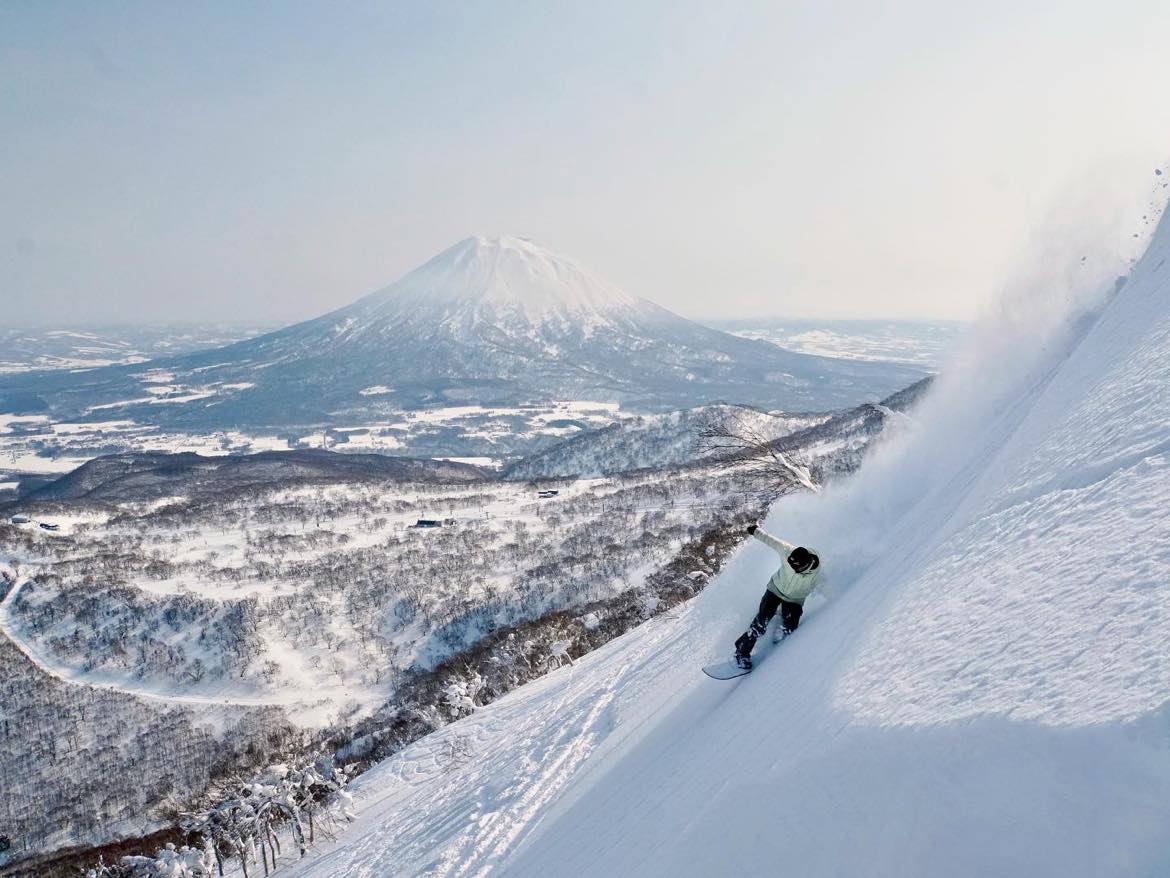 Snowboarder powder turn in front of Mt Yotei, Niseko